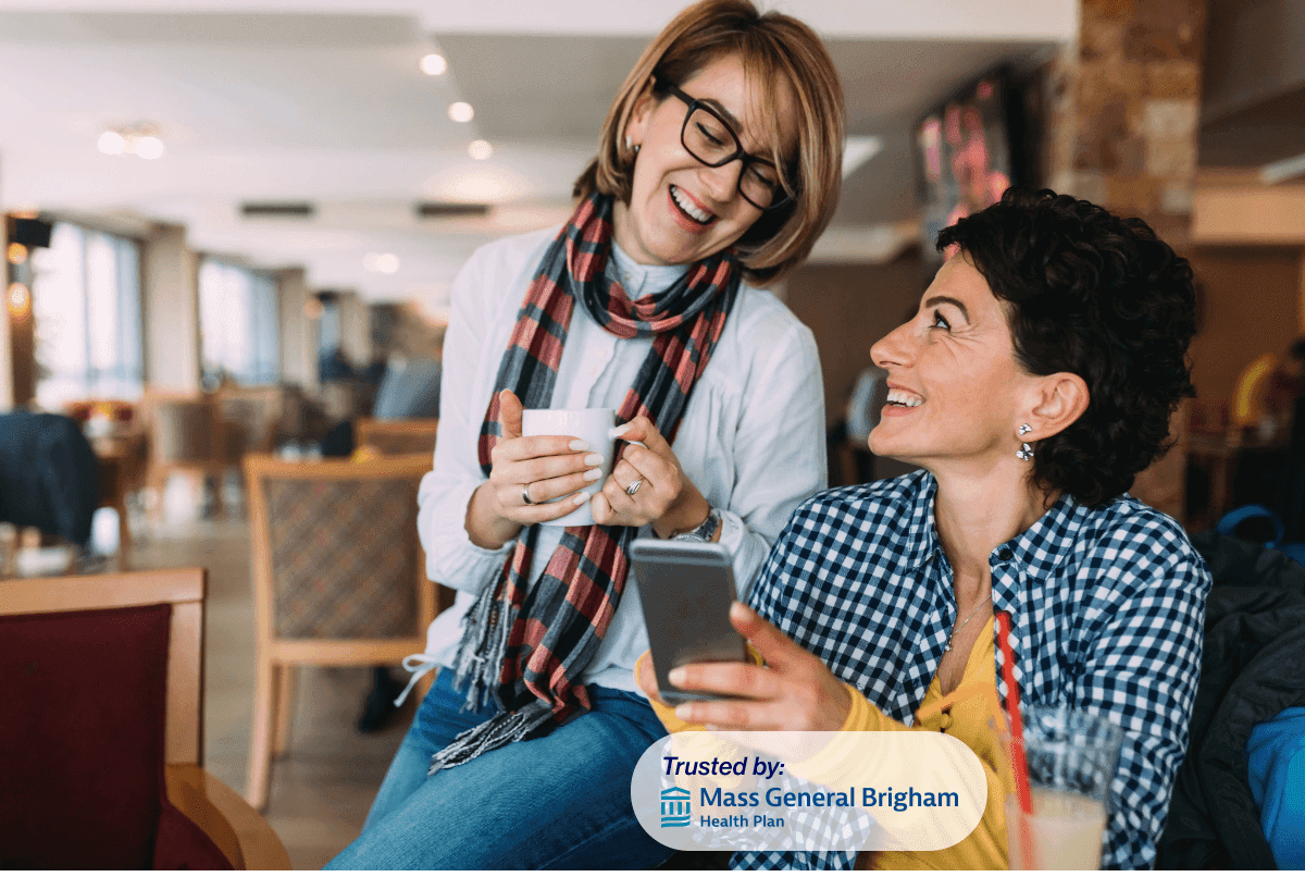 two women sitting next to each other. On their phones at work